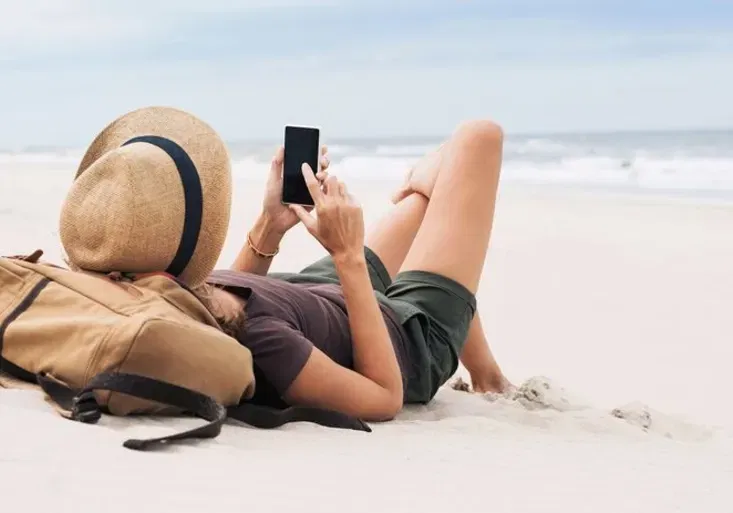 Woman using smart phone on a beach