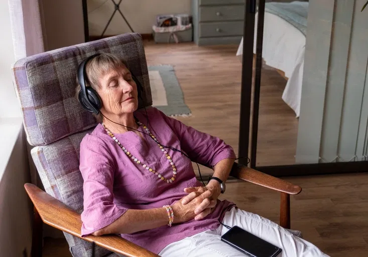 Senior woman sits and relaxes with music in her ears
