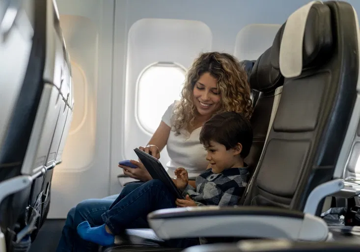 Loving mother and son playing with tablet during a flight looking very happy